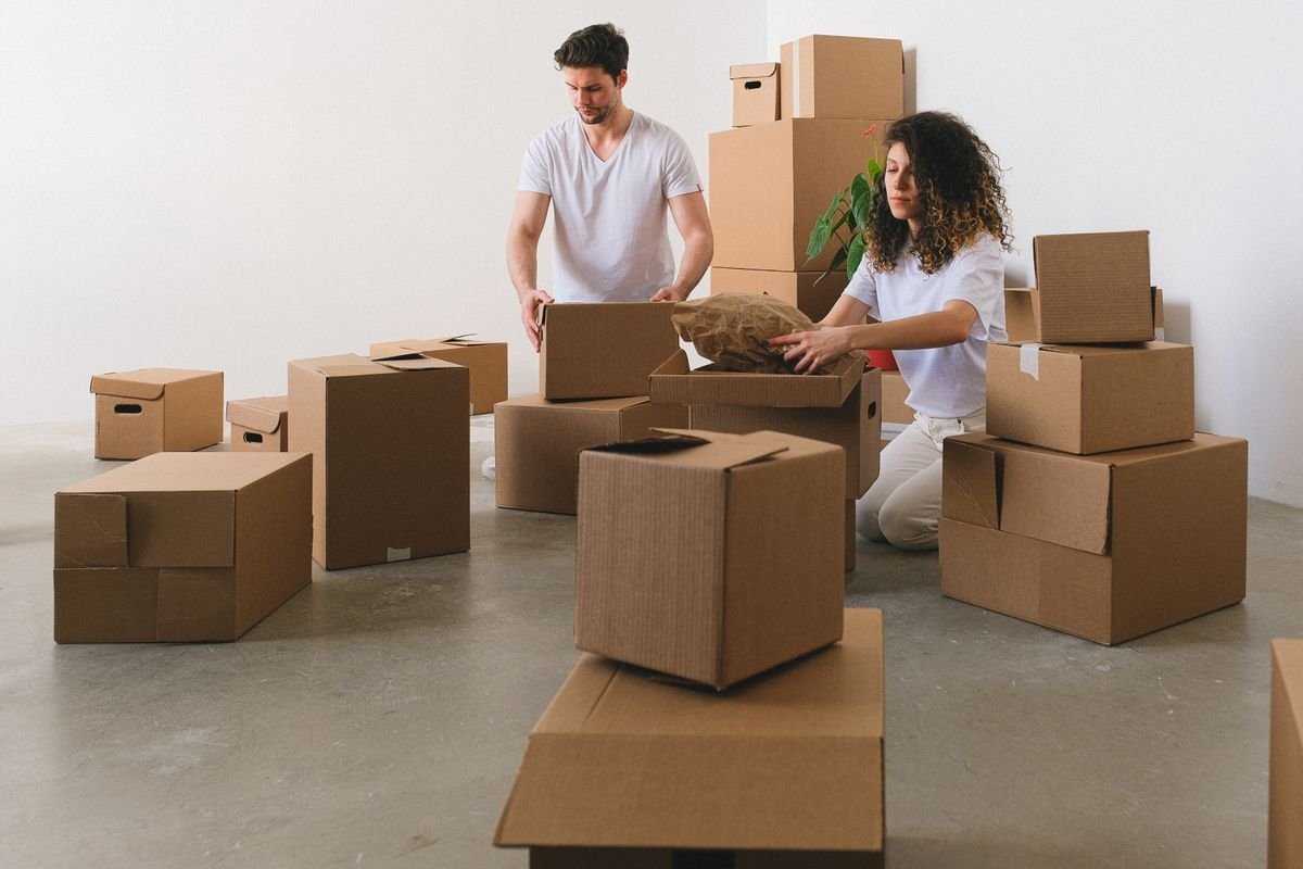 Dubai Rental Costs Beyond Rent: Your 2026 Move-In Budget 1 Couple organising cardboard boxes during a home move